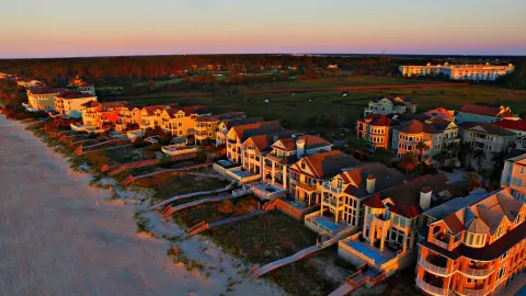 Stunning aerial shot of luxurious beachfront homes on Hilton Head Island at sunset, showcasing coastal beauty.