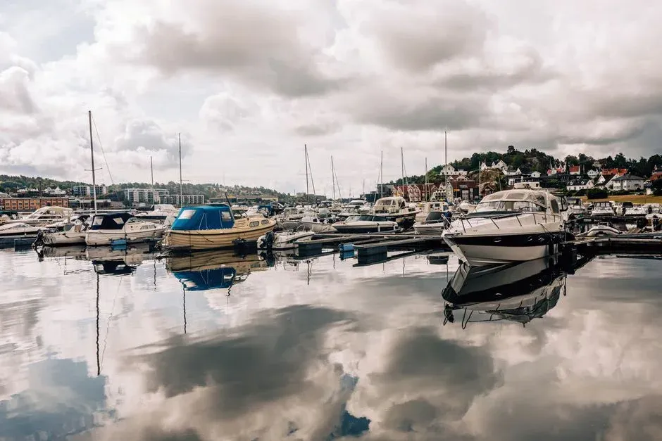Boats moored in a calm marina under a cloudy sky