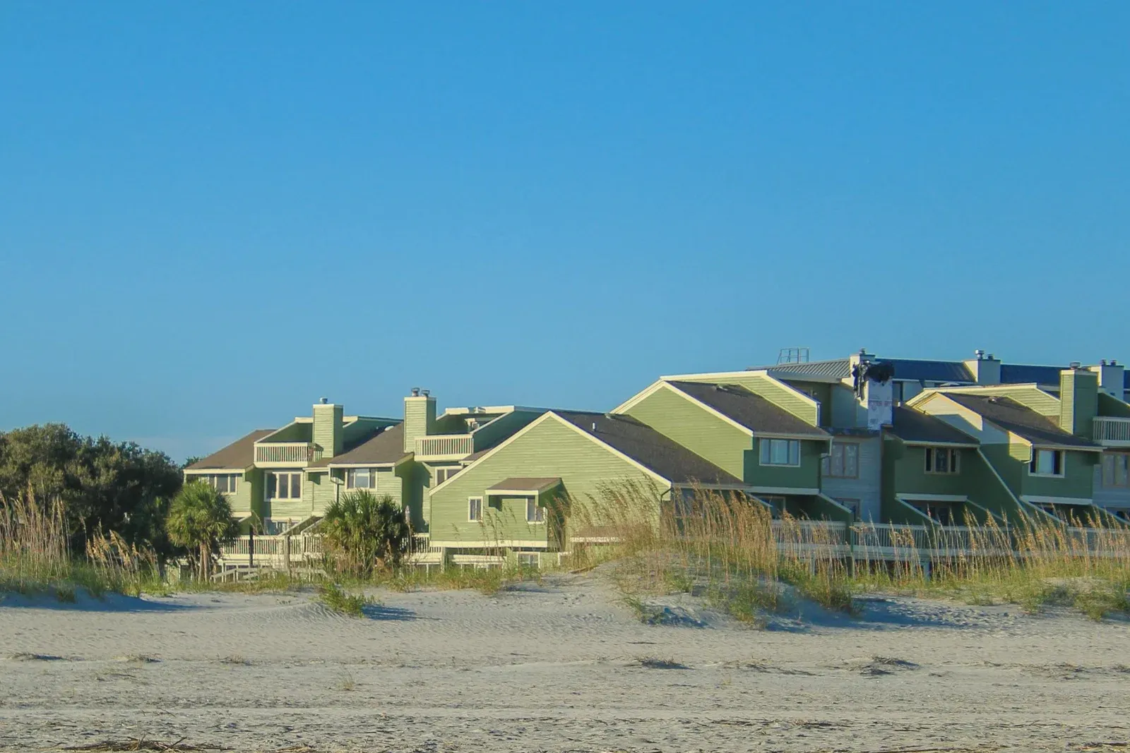 Green beachfront condominium buildings behind the dunes on a Lowcountry beach
