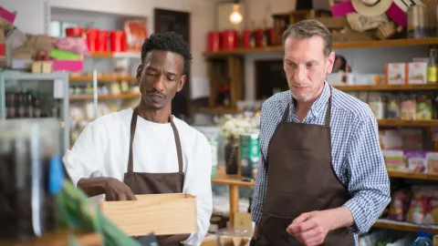 Two male employees organizing products in a cozy grocery store.