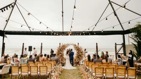 A picturesque wedding ceremony held outdoors under a canopy by the sea. Perfect setting for a romantic event.