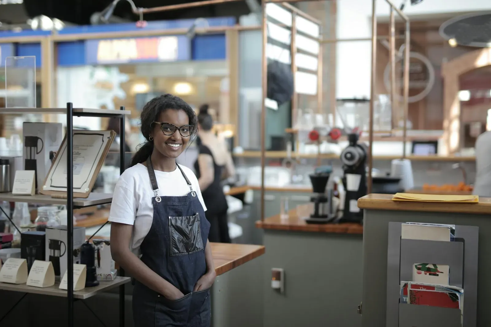 Smiling barista standing in a stylish café, showcasing entrepreneurial spirit.