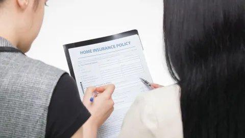 A couple reviewing a home insurance policy document together at a table.
