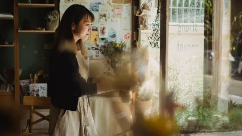 Side view of Asian woman  preparing cozy floral workshop for working day