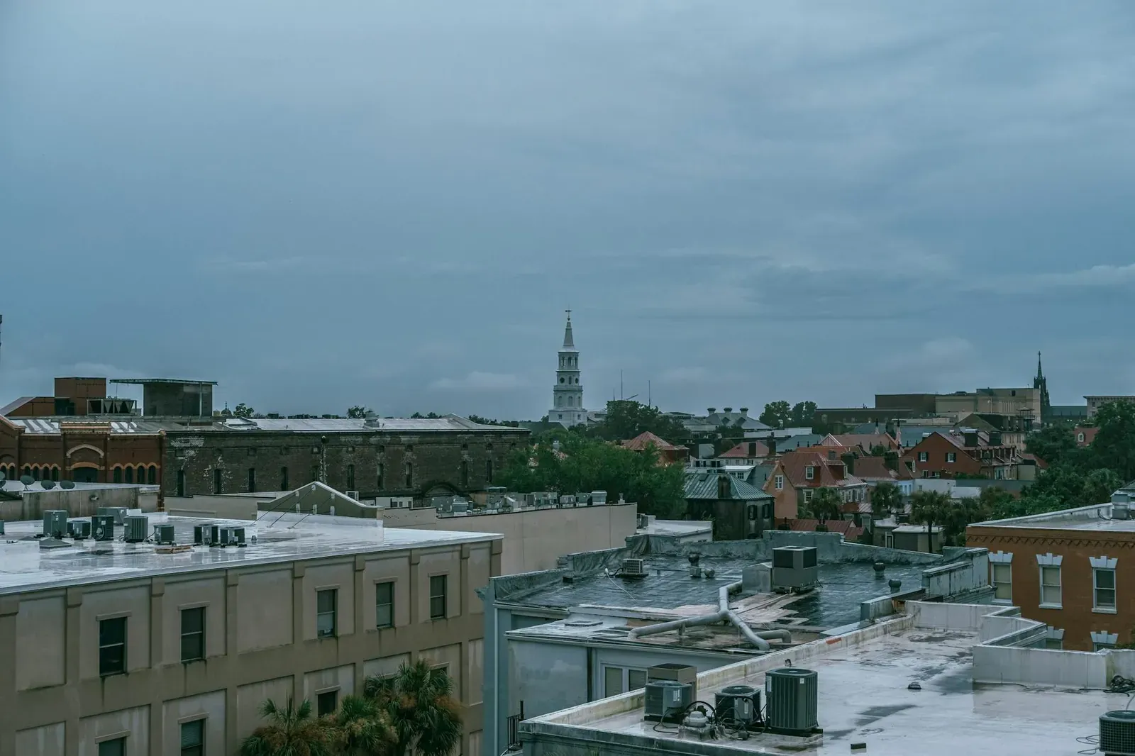 Aerial cityscape of Charleston, SC showcasing historic architecture under a cloudy sky.