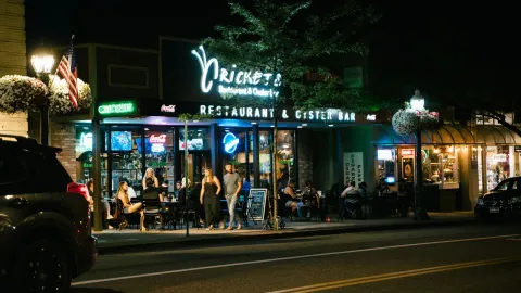 A bustling urban nightlife scene at a restaurant and oyster bar, with people dining outside.