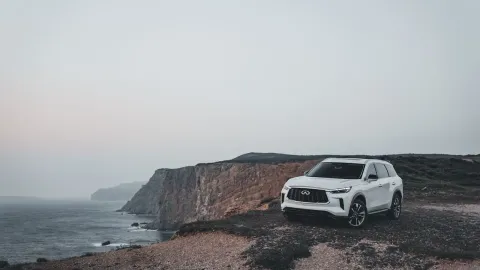 A stylish SUV parked beside majestic coastal cliffs at dusk, capturing the essence of adventure and travel.