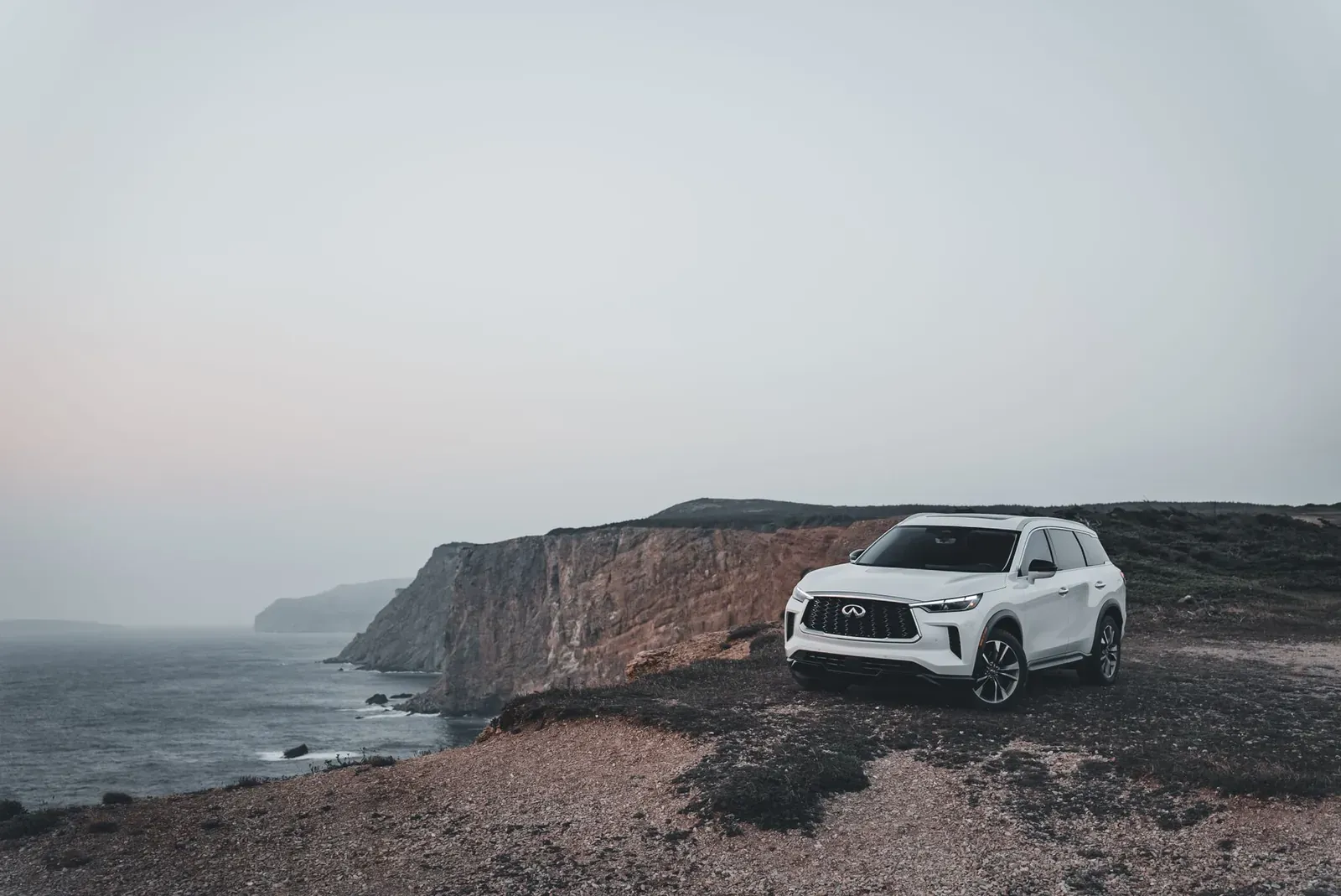 A stylish SUV parked beside majestic coastal cliffs at dusk, capturing the essence of adventure and travel.