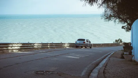A car parked on a coastal road in Carthage, Tunisia, offering a tranquil sea view.