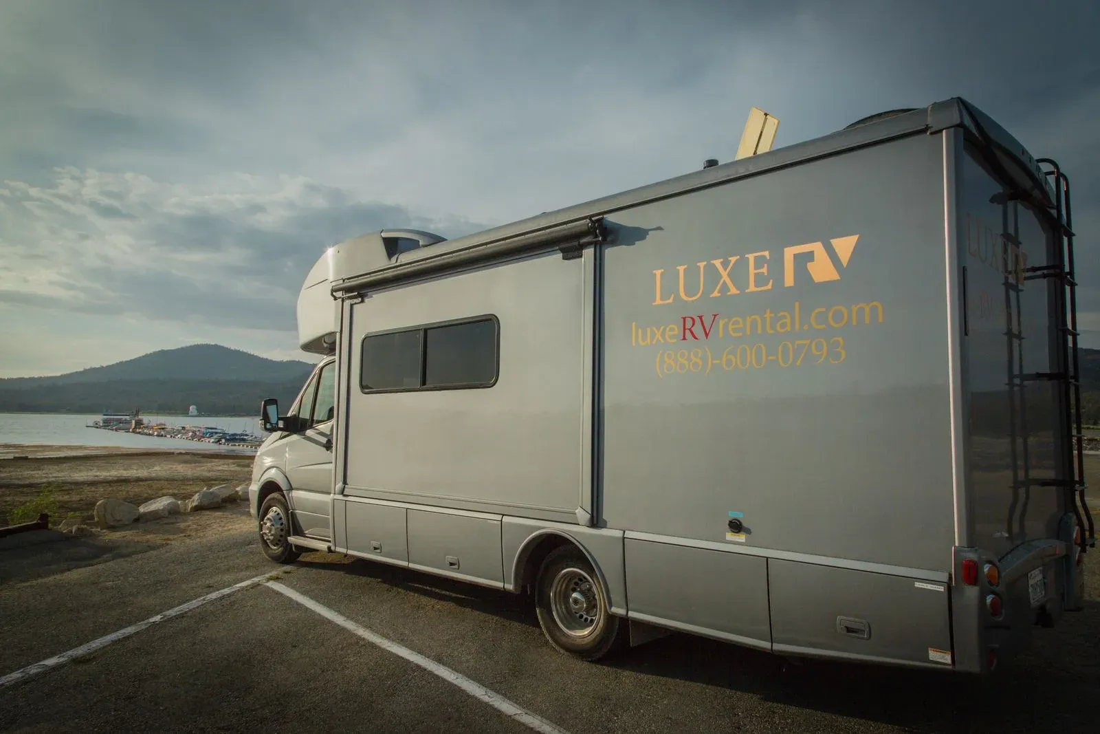 A modern RV parked beside a scenic lake