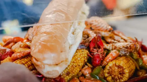 Close-up of a savory seafood boil with shrimp, crab, corn, and bread. Perfect for food lovers.