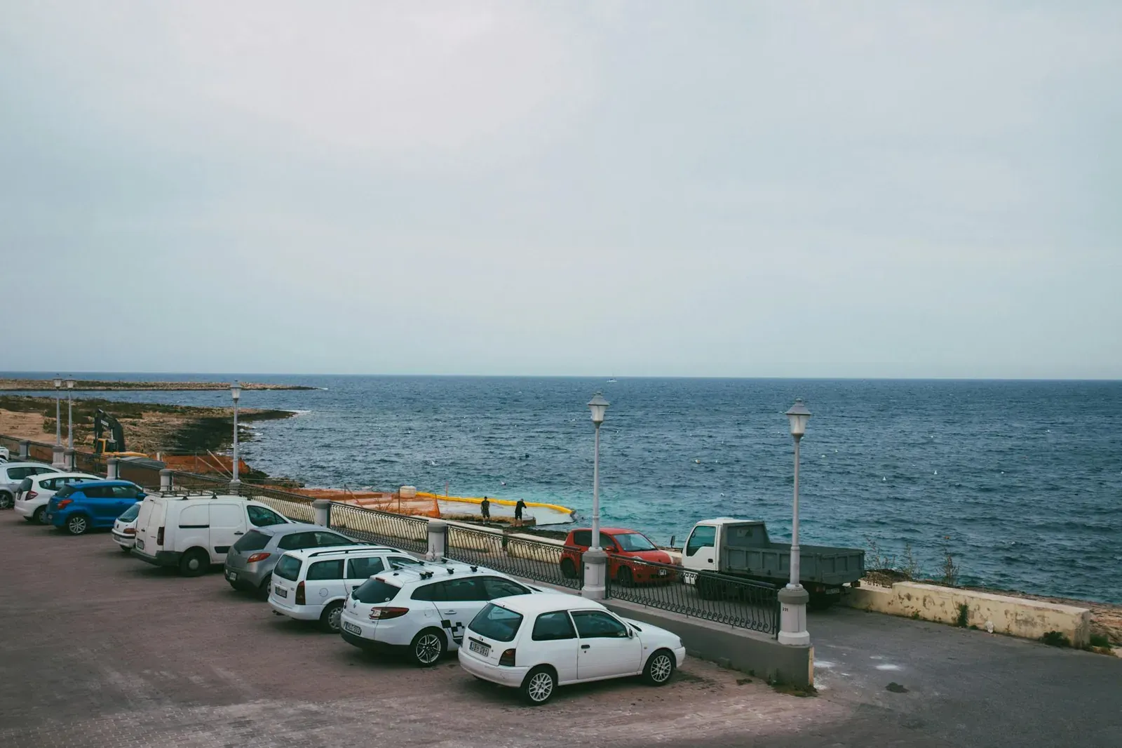 A serene seaside parking area overlooking the expansive ocean under a clear sky.