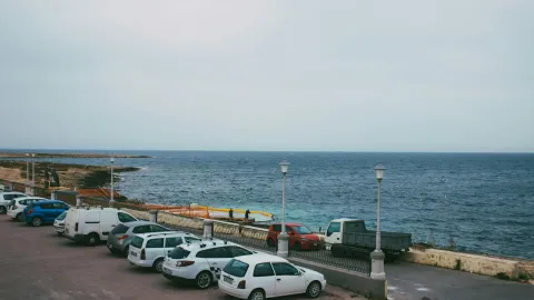 A serene seaside parking area overlooking the expansive ocean under a clear sky.