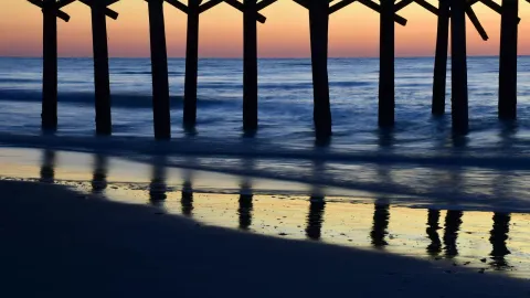 Serene sunset casting colorful reflections under Myrtle Beach pier.