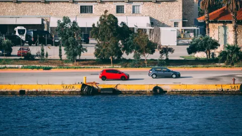 A vibrant urban waterfront scene with cars parked alongside an industrial-style building.