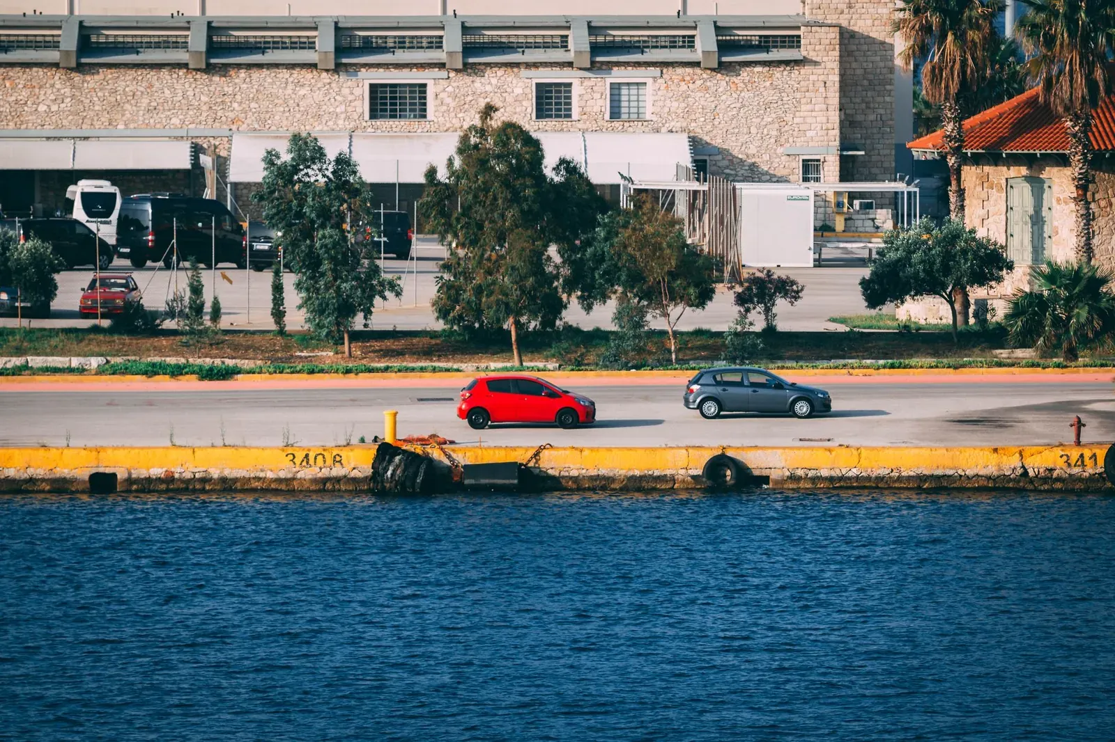 A vibrant urban waterfront scene with cars parked alongside an industrial-style building.
