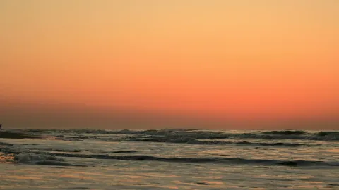 A tranquil sunset at Hilton Head Island with vibrant orange skies and gentle ocean waves.