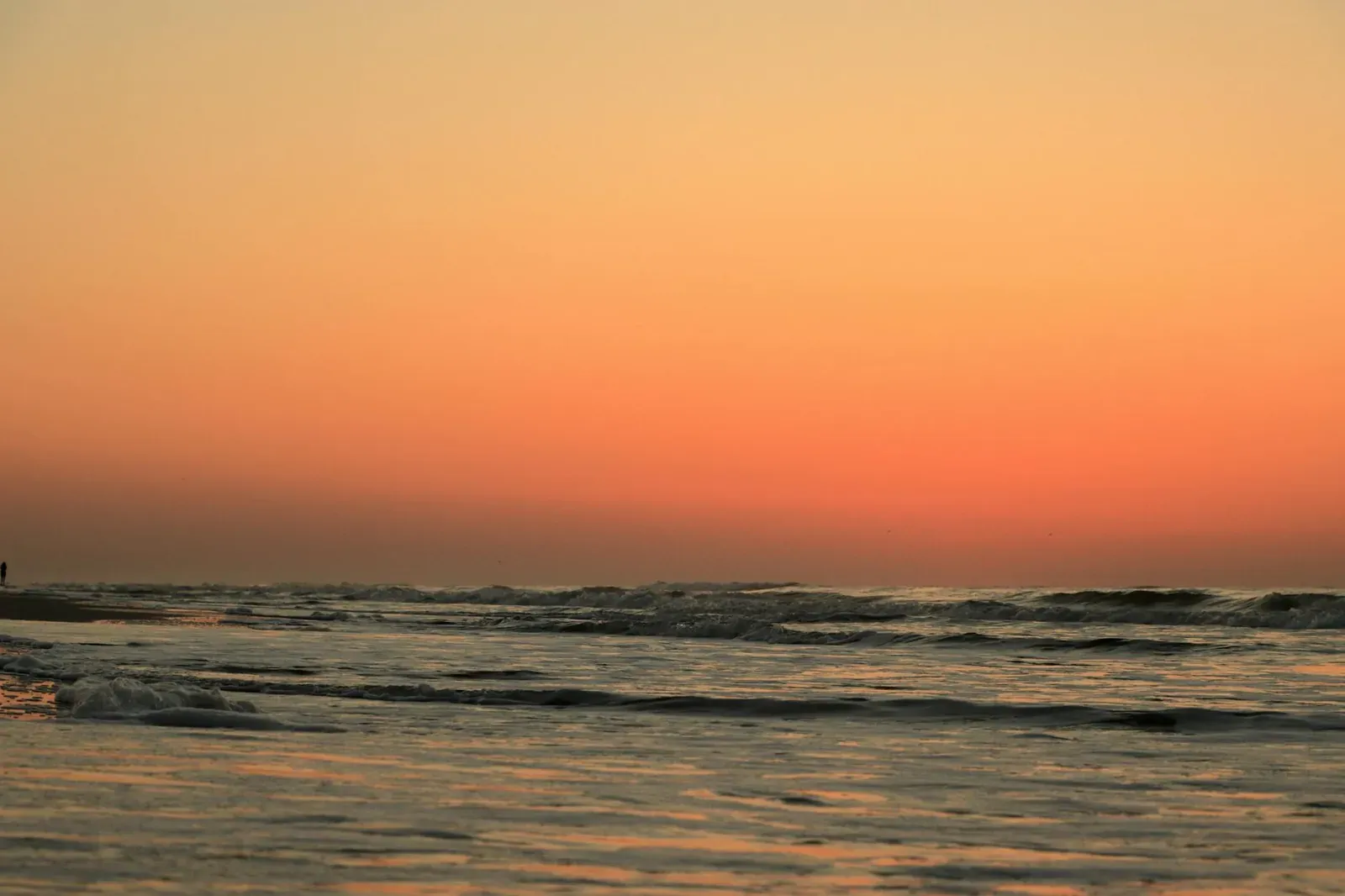 A tranquil sunset at Hilton Head Island with vibrant orange skies and gentle ocean waves.