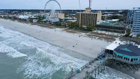 Aerial shot of Myrtle Beach with iconic pier and ferris wheel, capturing coastal beauty.