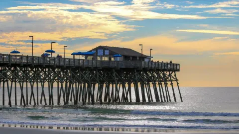 Peaceful sunset view of Garden City Pier extending into the Atlantic Ocean, capturing a tranquil coastal scene.