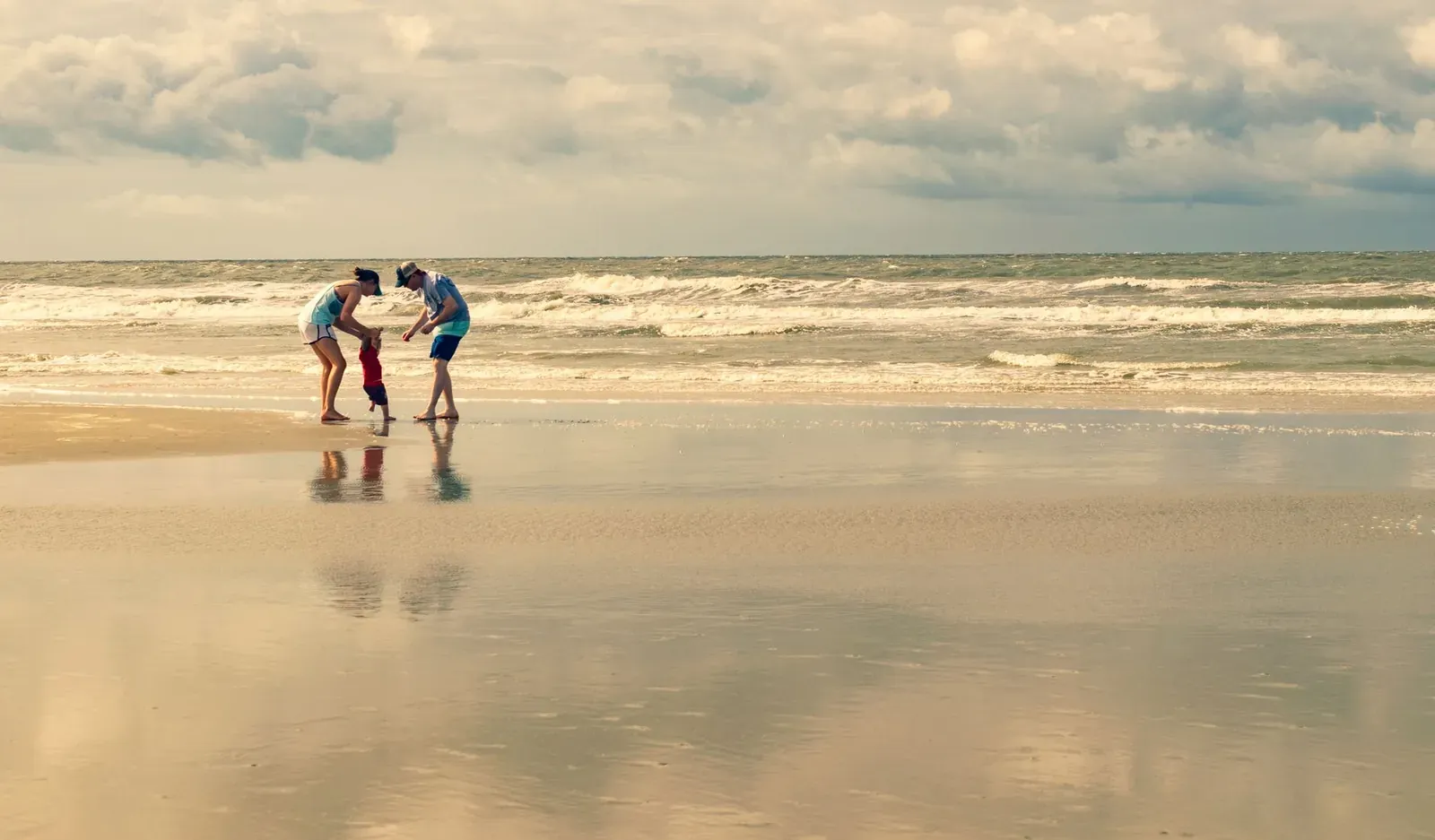 A family enjoying playtime by the shore at Sunset Beach, NC under a clear sky.