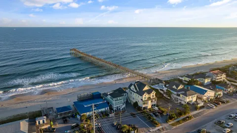Stunning aerial view of Surf City, NC showcasing the pier and ocean waves under a serene sunset.