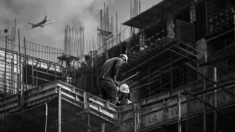 Black and white photo showing construction workers on an urban building site.