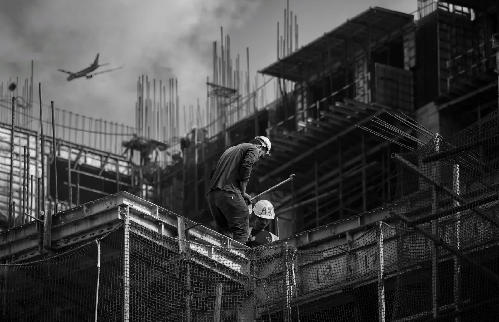 Black and white photo showing construction workers on an urban building site.